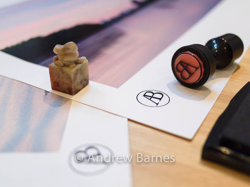A Chinese soapstone seal alongside a rubber stamp showing the photographer Andrew Barnes' AB logo. 